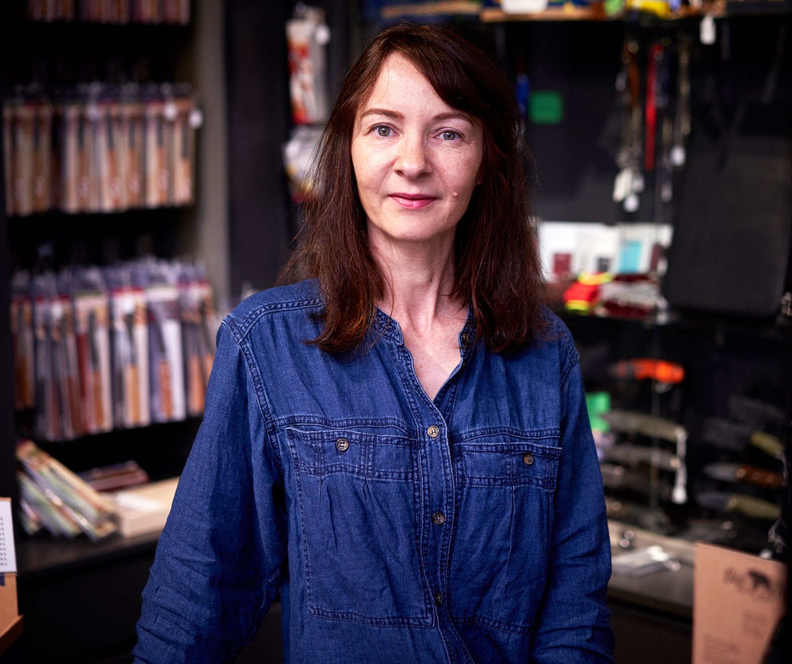 Eine brunette Frau namens Manuela in einer blauen Jeansbluse im Verkaufsraum der Altonaer Silberwerkstatt