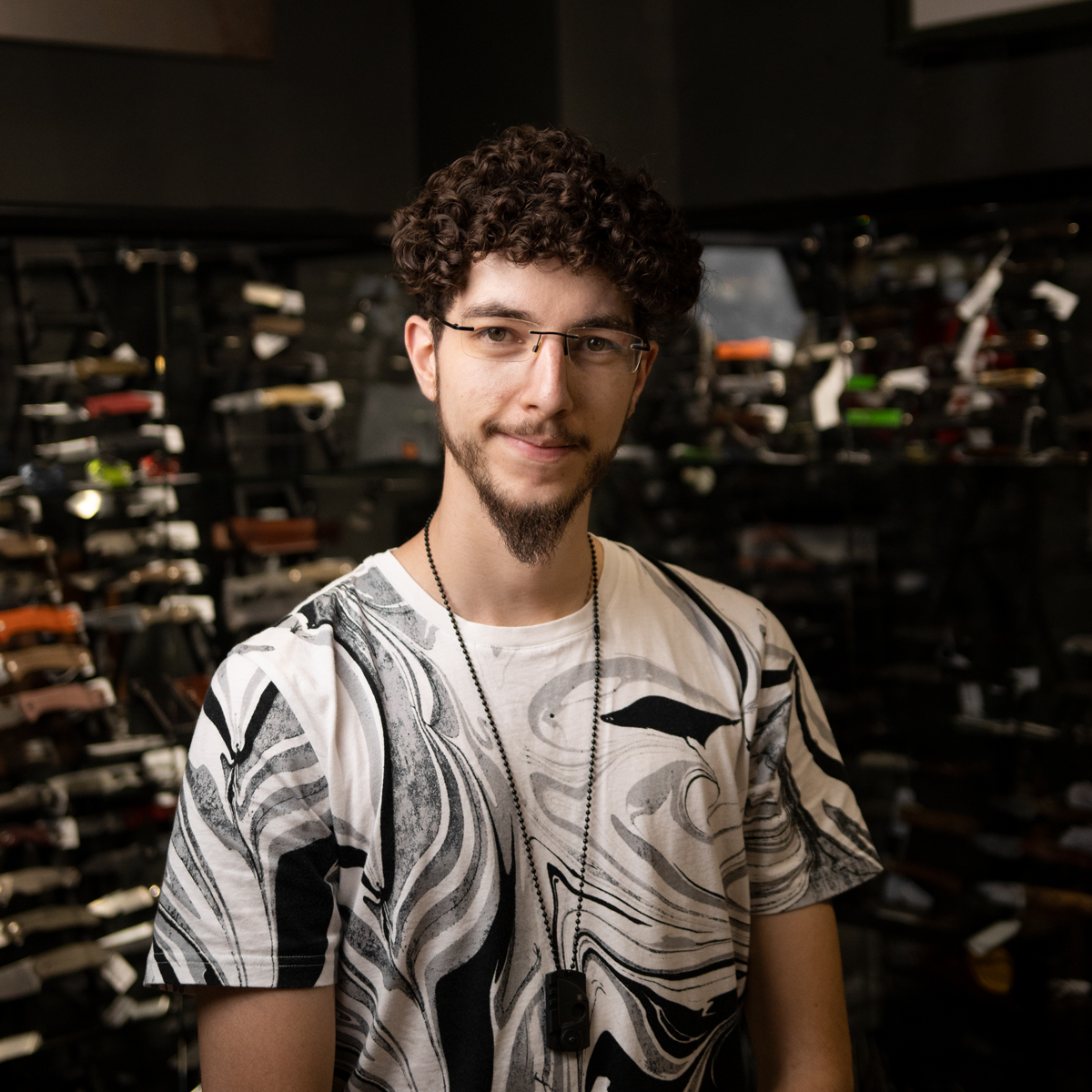 Ein junger brunetter Mann mit Locken,und Brille im Verkaufsraum der Altonaer Silberwerkstatt stehend